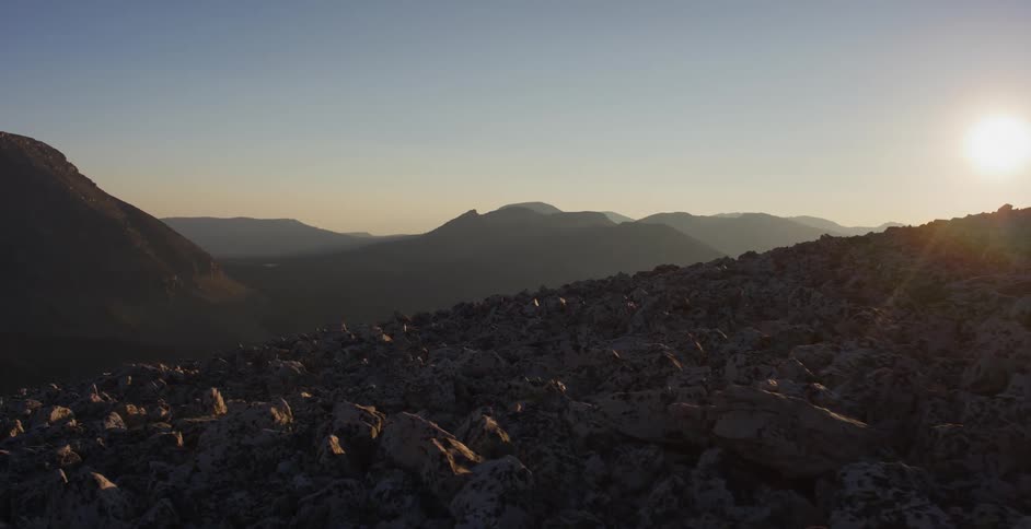 Rocks piled on a slope with mountains in the distance