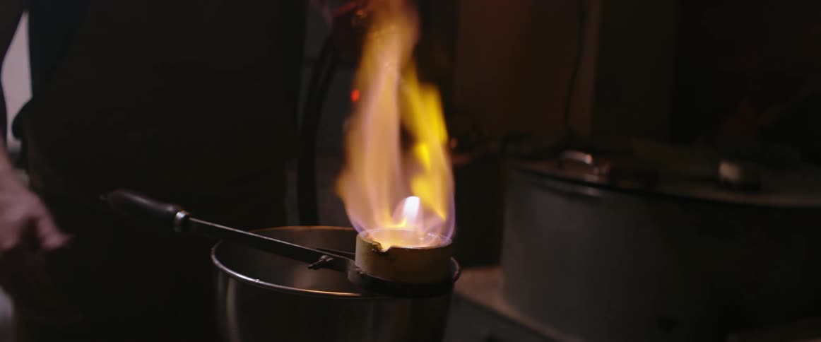 Man holds a burning torch as he torches a crucible