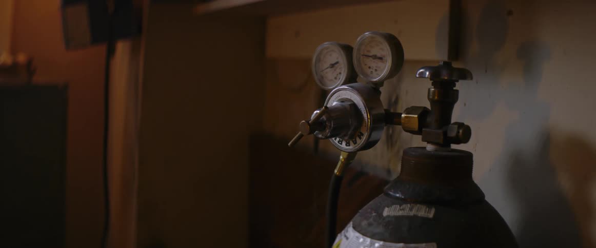 A tank with gauges on it sitting in a workshop