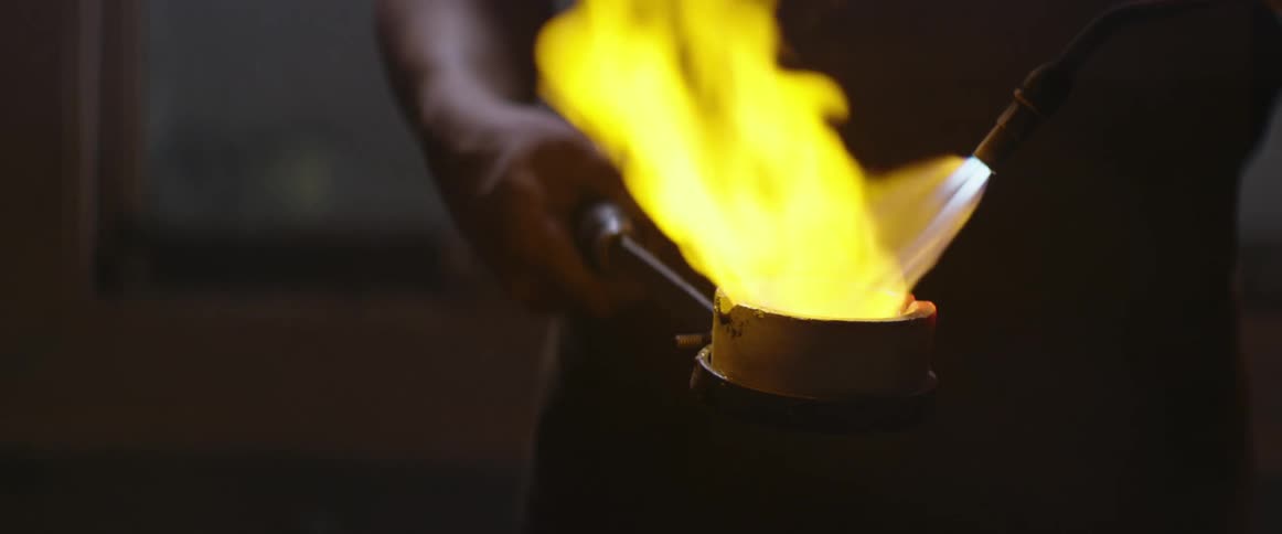 Man uses a torch to melt metal in a crucible 2