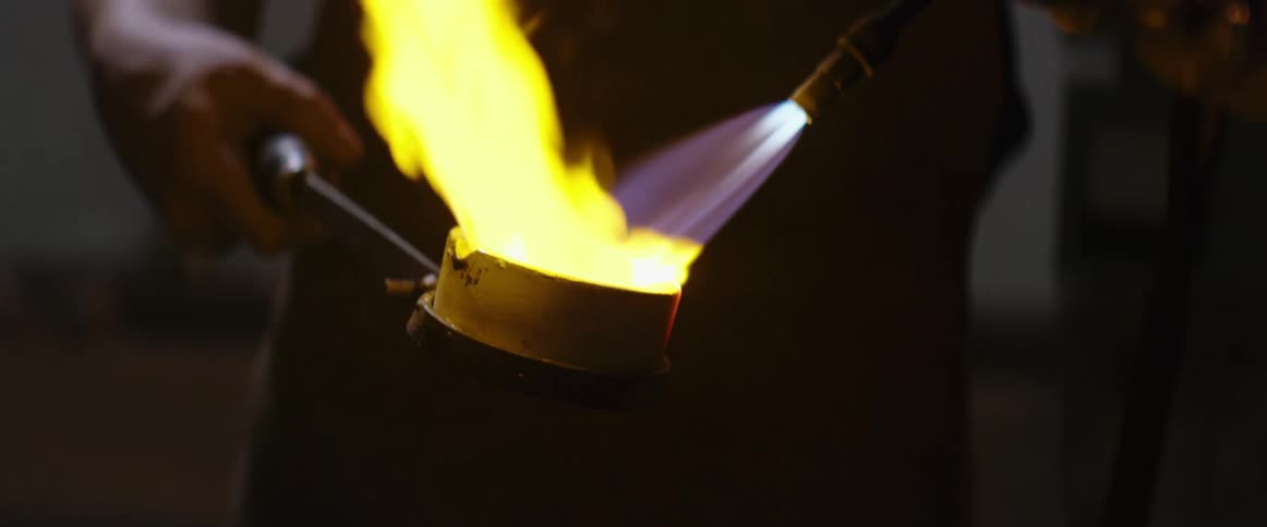 Man uses a torch to melt metal in a crucible 3