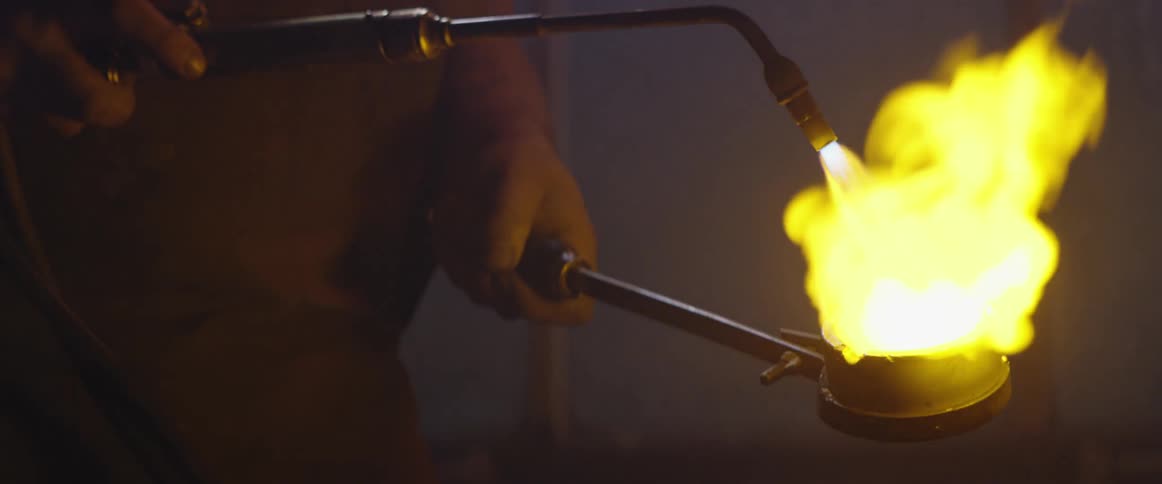 Man uses a torch to melt metal in a crucible 6