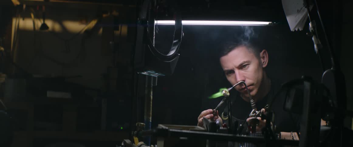 Man sitting in workbench uses torch on jewelry