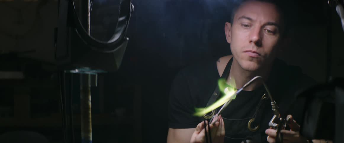 A man using a blowtorch on a metal ring causing the flames to turn green