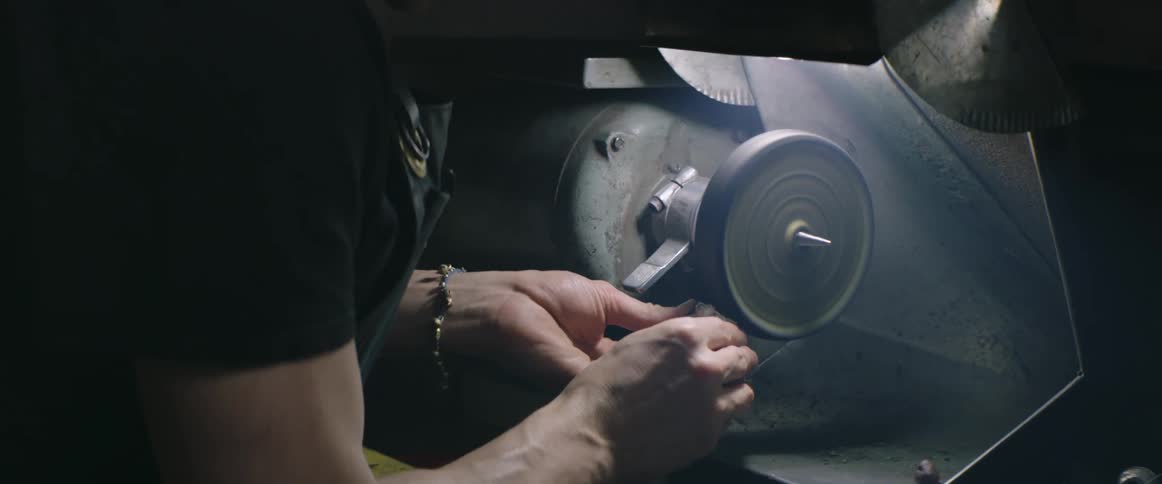Man uses an electric grinder on a small stone
