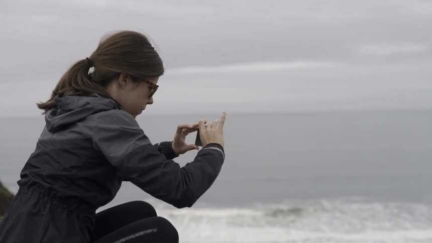 A woman in black takes a video with her phone