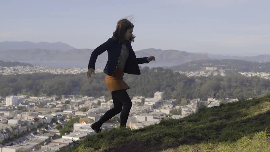 A woman jumps up a hill