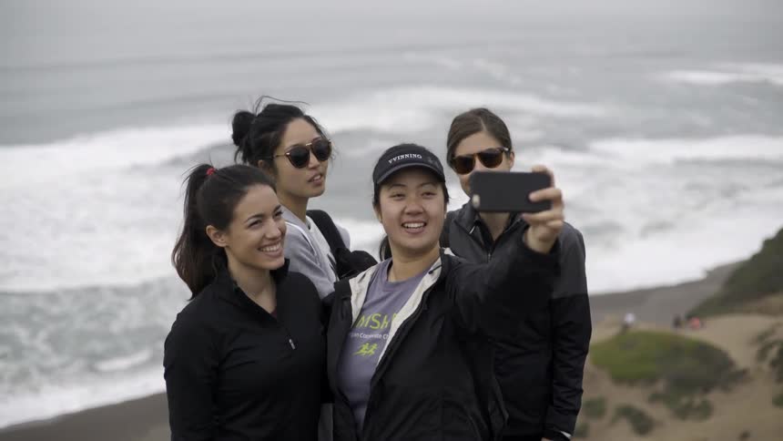 Women taking a selfie by the ocean with carefree joyful summer vibes.