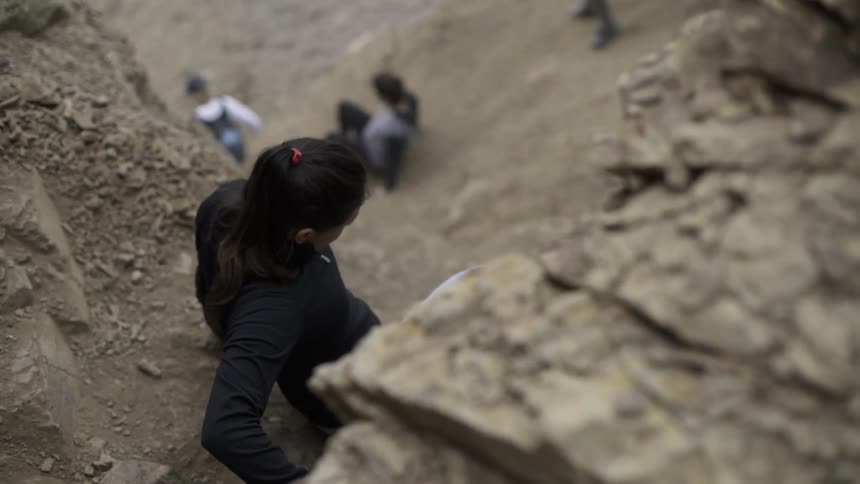 People carefully climbing down rocky terrain in nature with adventurous movement.