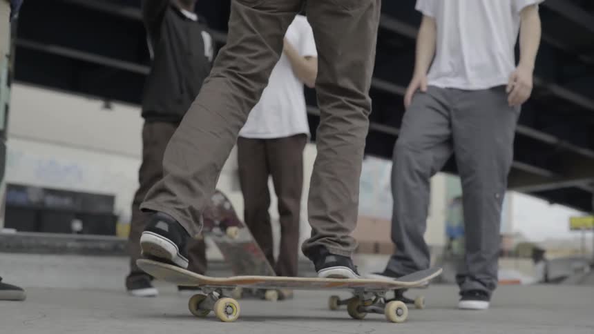Teenage boys with skateboards stand in an urban skate park