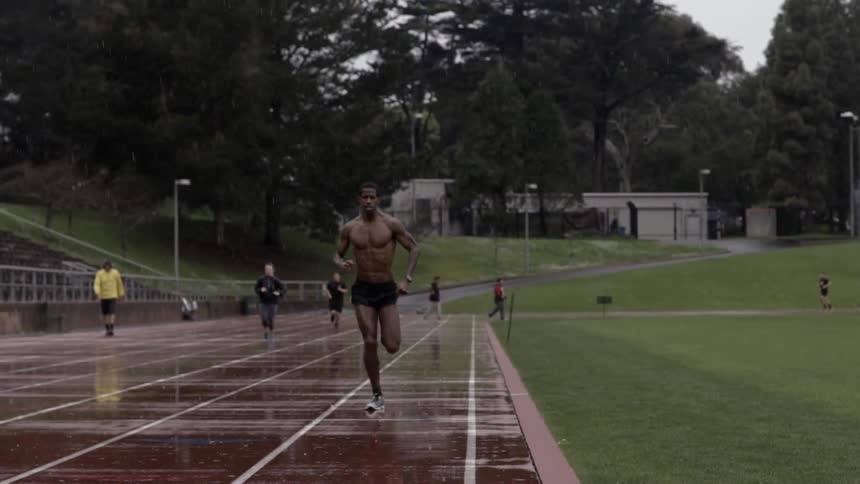 People jogging down wet track in rain with gritty determined group energy.