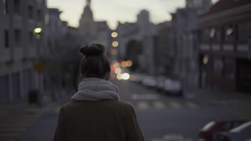 Woman walking through city on chilly evening with cozy reflective mood.