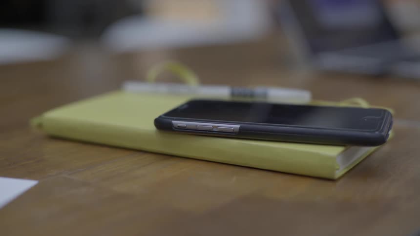 A book and phone are sitting on a desk