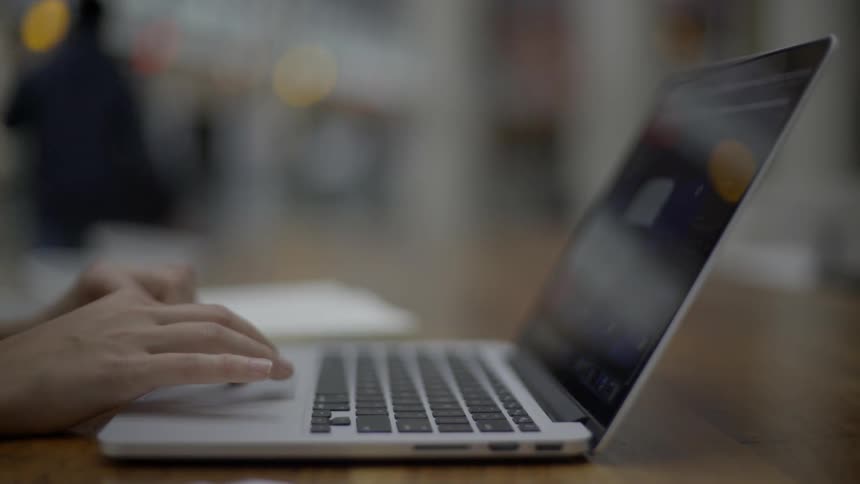 A person uses a laptop keyboard and trackpad