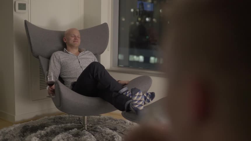 Man relaxing in chair with glass of wine in calm evening mood.
