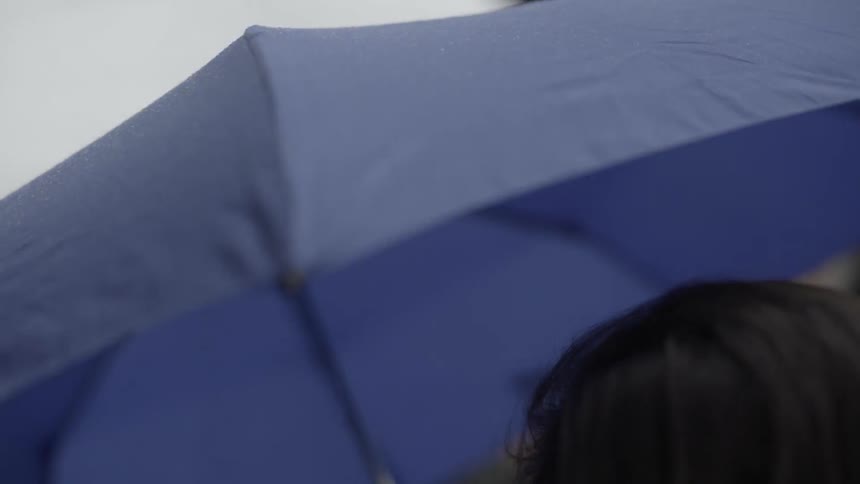 Two girls walking under blue umbrella in rain with joyful friendship vibe.