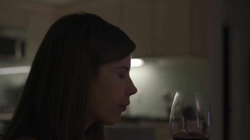 Young woman sipping wine with relaxed graceful mood in cozy atmosphere.