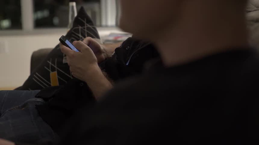 Man planning on phone while sitting on couch with relaxed everyday vibe.