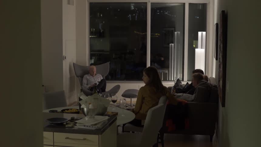 Friends sitting and talking in apartment at night with warm intimate vibe.