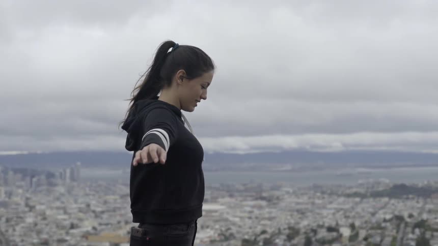 Woman balancing while walking on cloudy day with playful carefree energy.