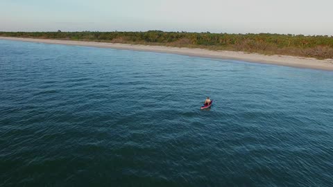 A single boat is sitting in the water by the beach