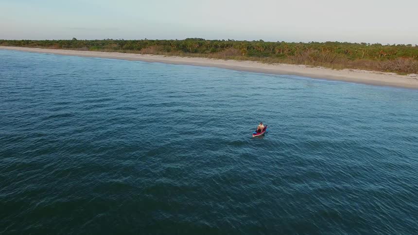 A single boat is sitting in the water by the beach