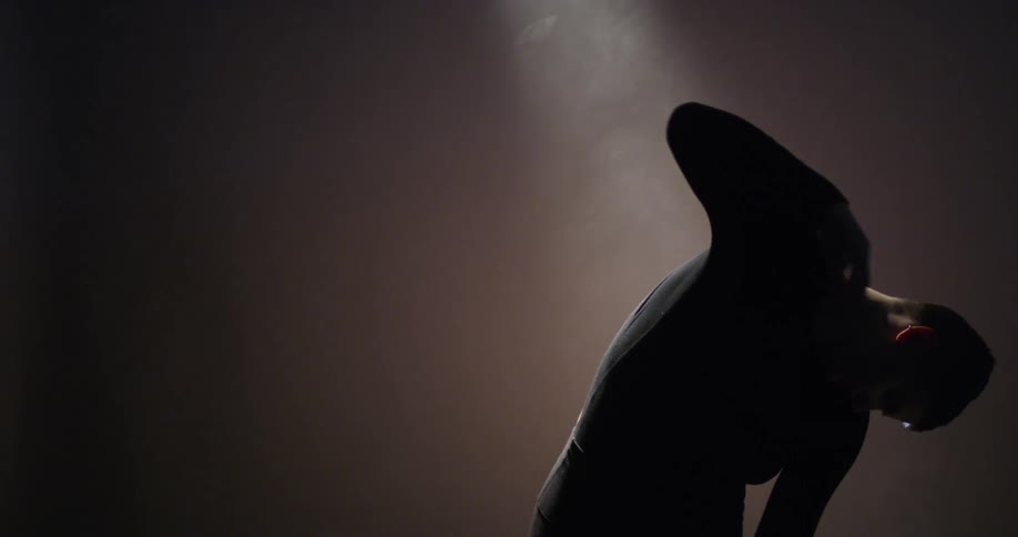 The silhouette moves in the darkness