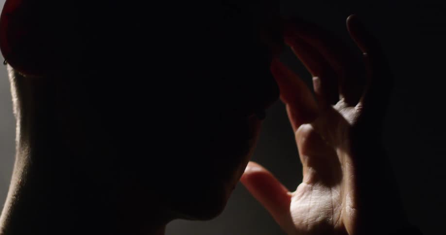 Man wearing a nose ring lifts his head and moves his hand towards his ear