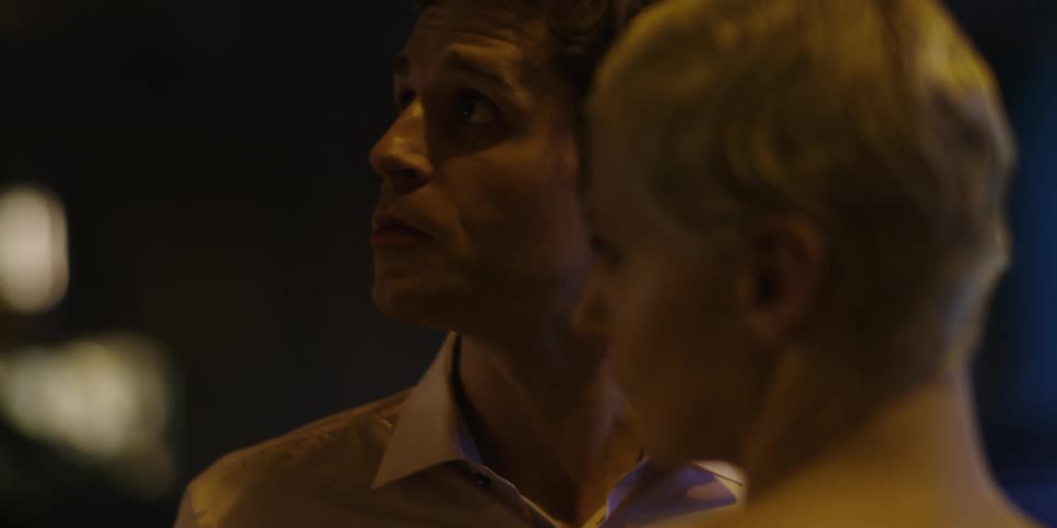 A man and a woman stand outdoors arguing