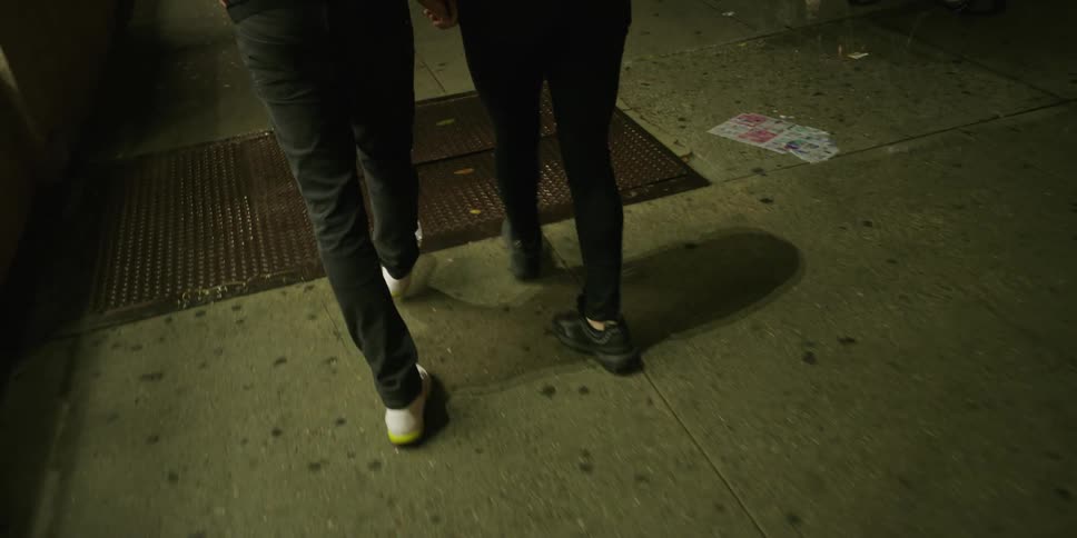 Two people walk on the sidewalk holding hands