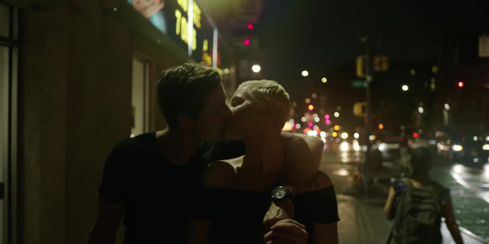 Couple walking on city streets at night kissing