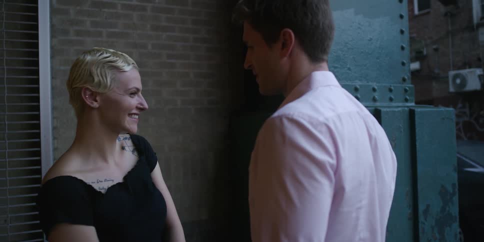 Woman smiles and blushes while talking to man