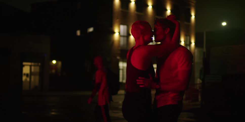 Man and woman stand and kiss in the street then begin to dance