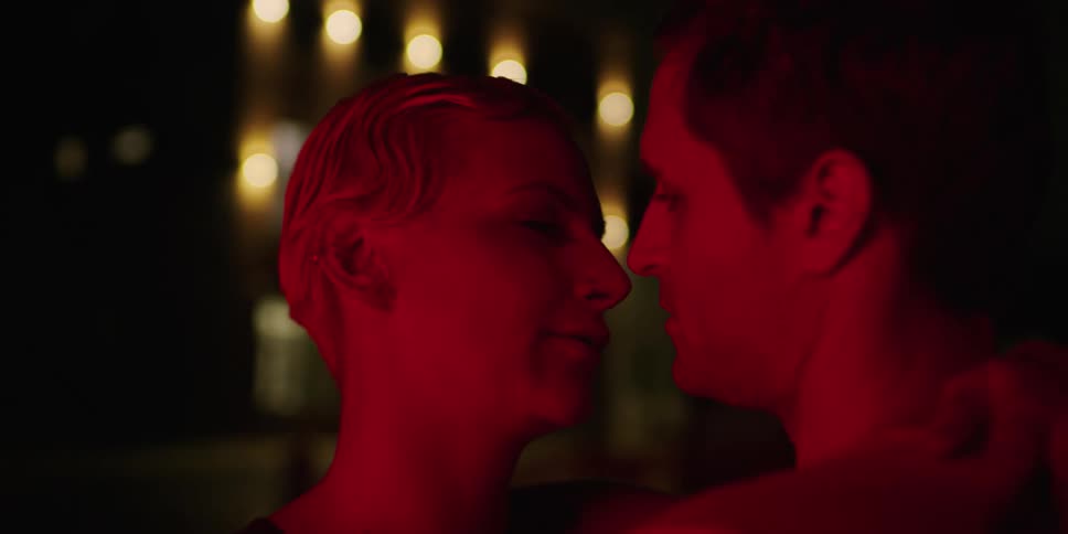 A man and woman slow dance close together outside at night