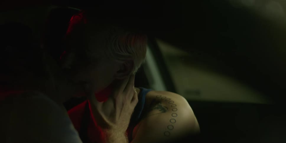 A man and woman are kissing in a car at night