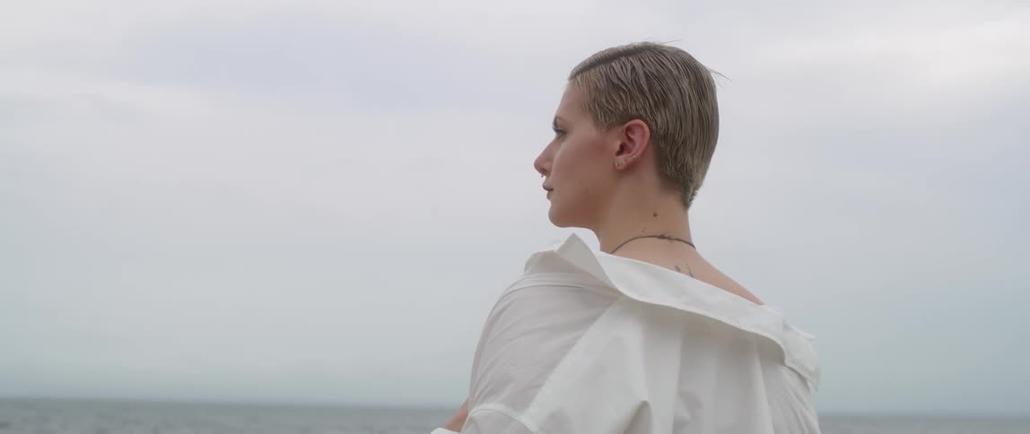 A woman is standing outdoors by a body of water