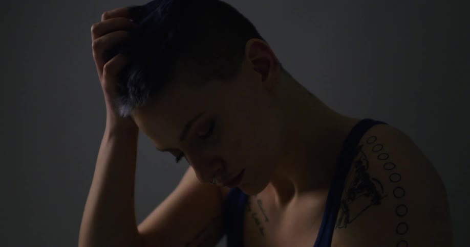 A woman with blue dyed hair rubs her head