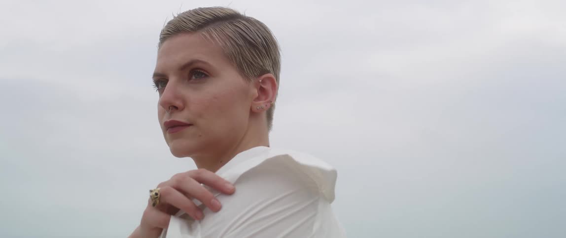 Woman stands outdoors on windy day grasping collar
