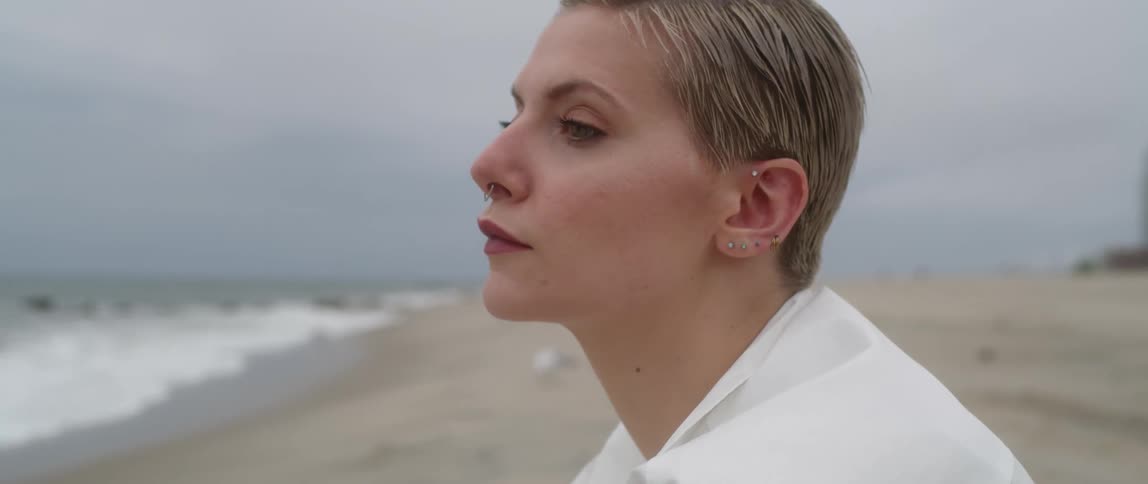 A white woman sits on a beach