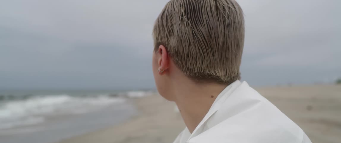 A woman sits on the beach and looks out at the water