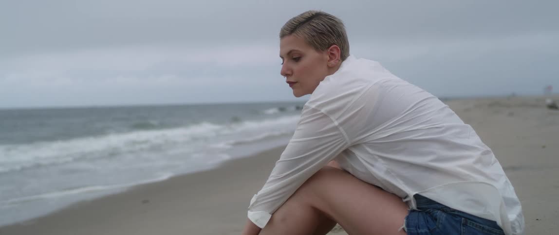 A woman with a shirt sitting on a sandy beach
