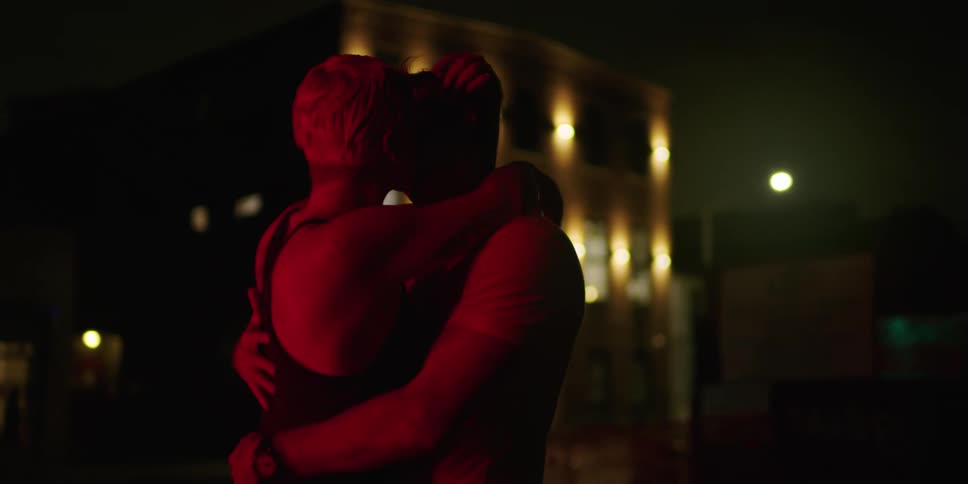 A couple dance and kiss outside of a building at night