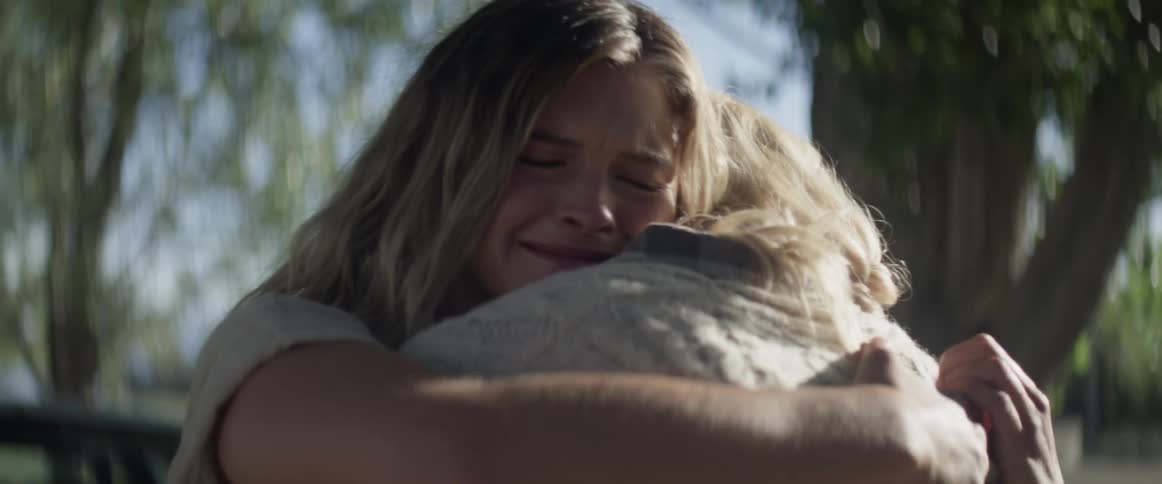 A woman standing next to her car turns around and hugs her mother as they cry together