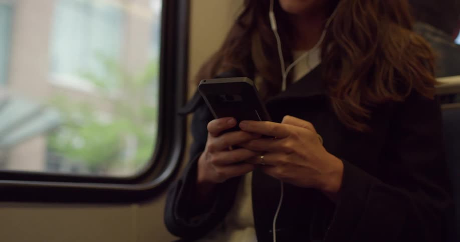 Woman scrolls through mobile phone while riding public transportation