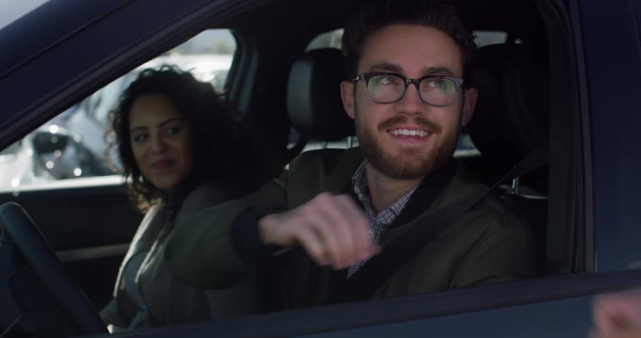 A man and woman are in a car and another man hands them the key