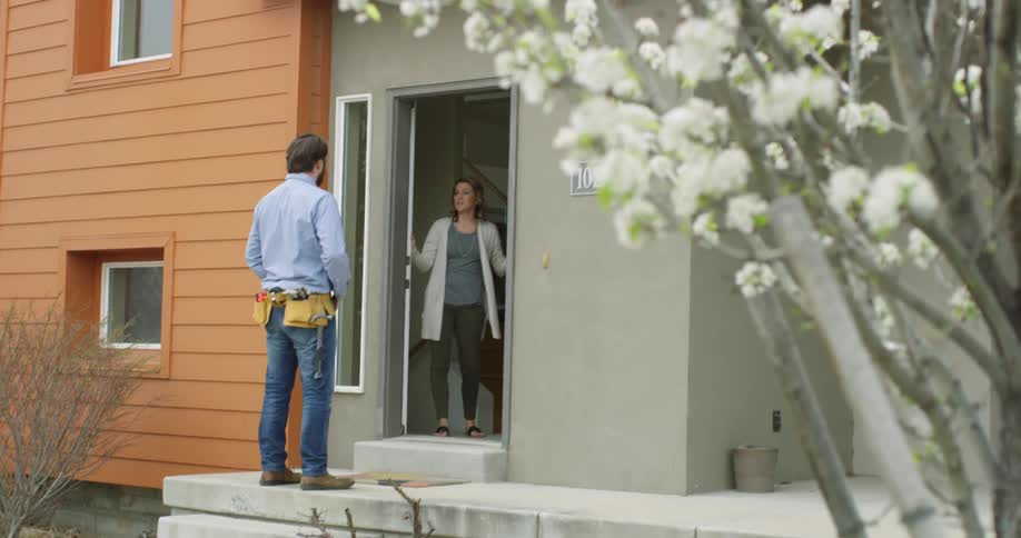A woman opens her door when a repairman knocks on it
