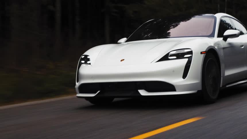 A white sports car speeds down a curved road