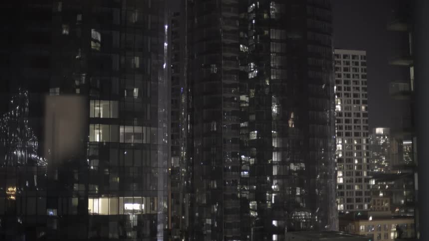 City skyline with illuminated skyscraper windows at night.