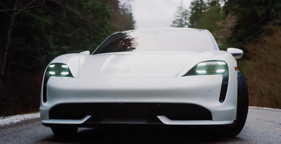 Porsche taycan parked on rural country road surrounded by pine trees