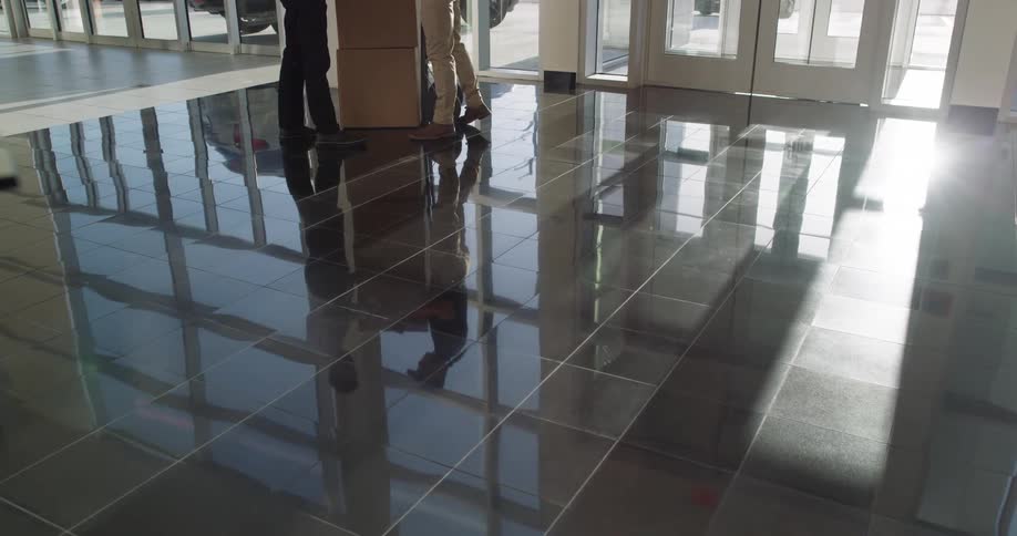 A delivery person rolls in boxes on a cart inside a building